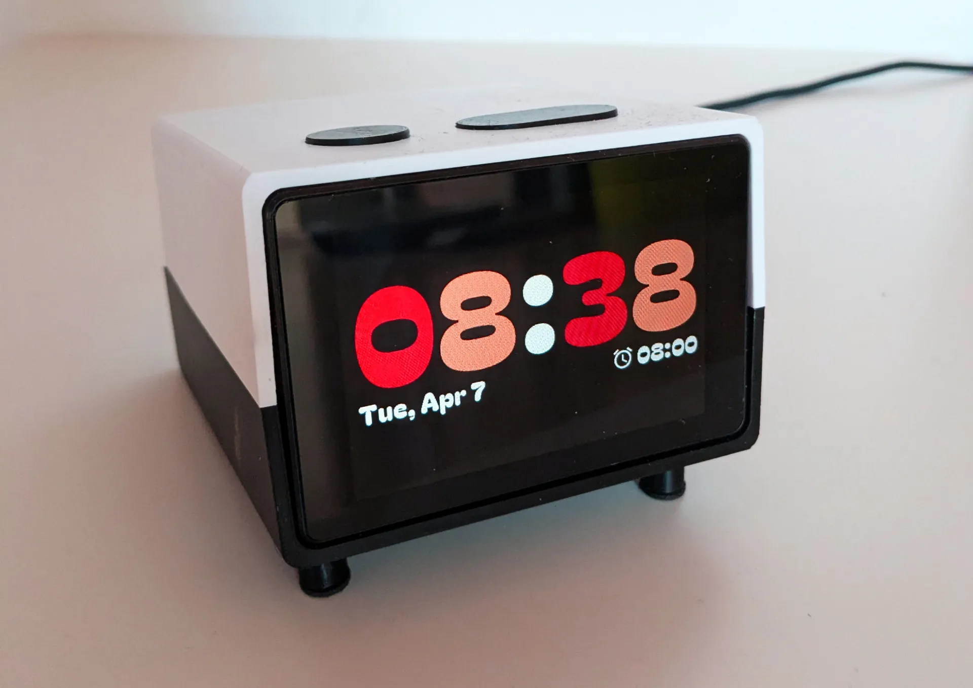 Smarter Wecker mit schwarzem Display, zeigt die Uhrzeit 08:38 in roten Ziffern sowie das Datum Dienstag, 7. April an.